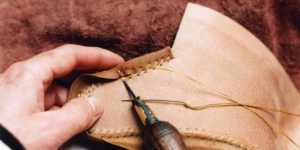 Artisan handsewing sole during the shoemaking process