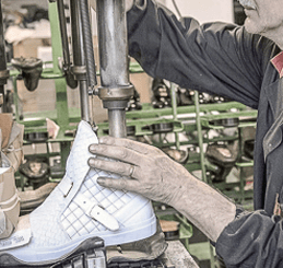 Artisan working on sneaker at sneaker manufacturer facility