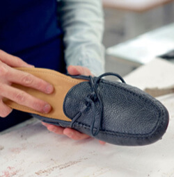 Artisan putting the insole into men loafer