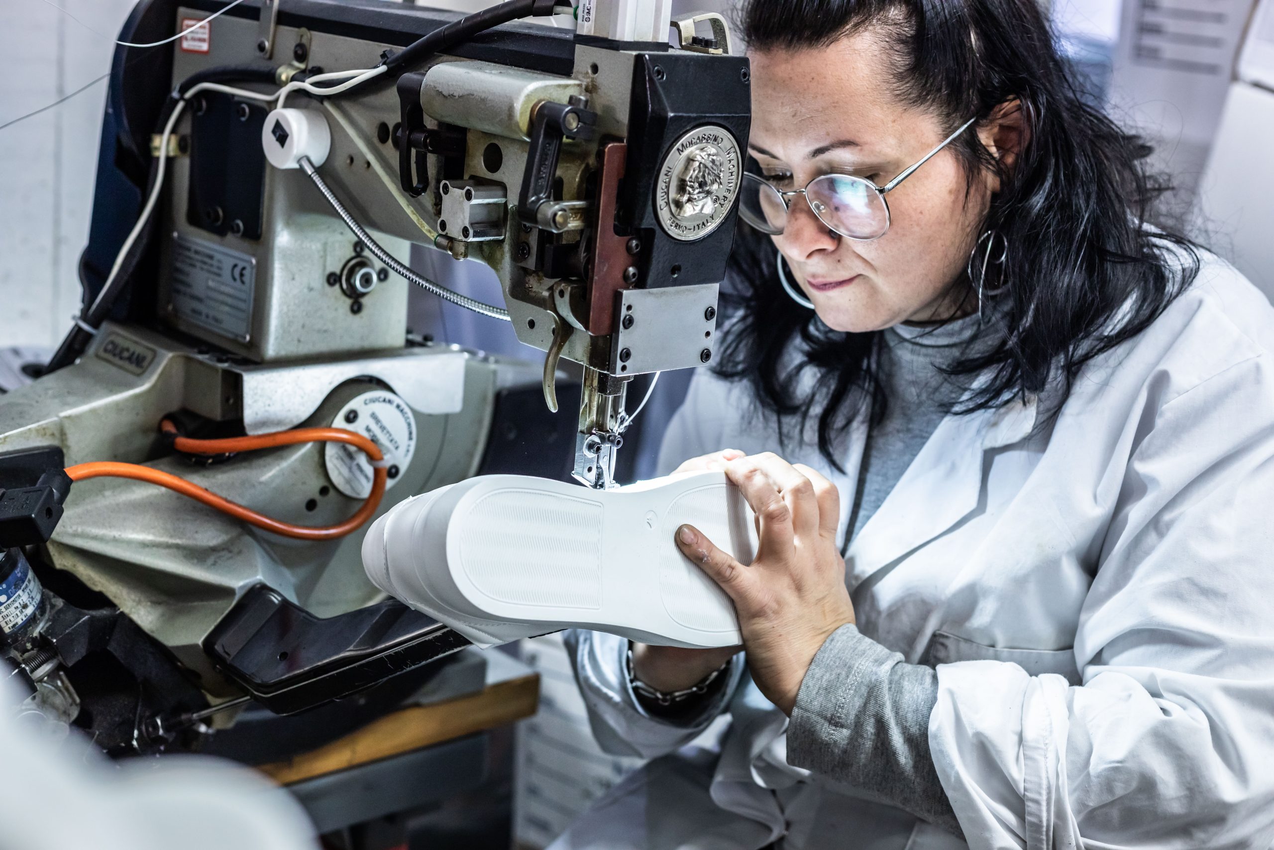 Female factory worker building vegan leather sneaker